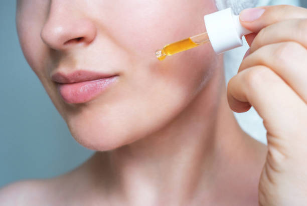 Close-up of a person applying retinol serum to their face as part of a skincare routine.